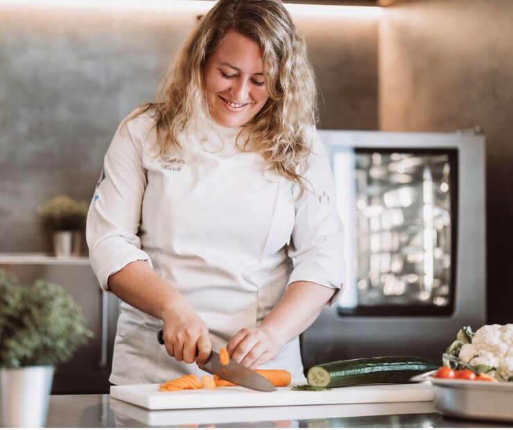 Köchin schneidet Gemüse in einer Küche